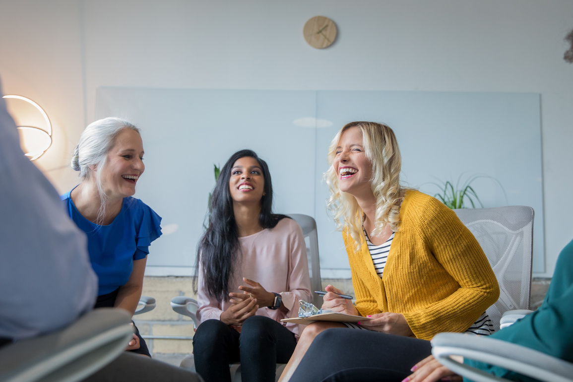 Diverse women laughing together during support group or networking meeting